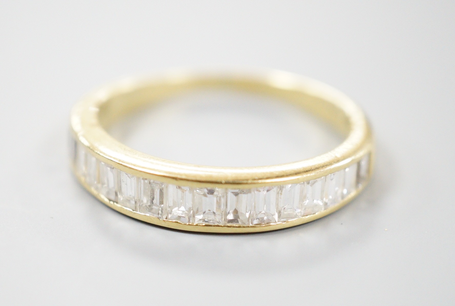 A modern 18ct gold and graduated baguette cut diamond set half eternity ring, size Q, gross 3.4 grams.